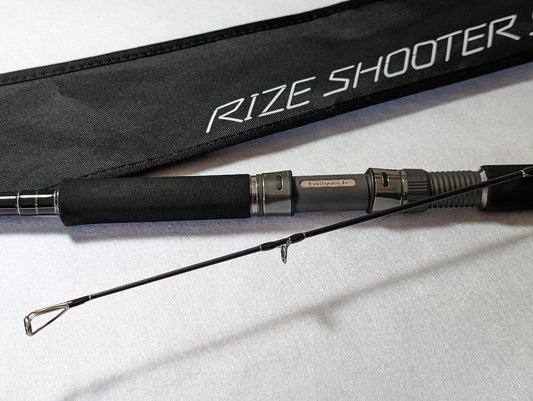 Tailwalk RIZE SHOOTER SSD S910H Shore Jigging Rod with a black butt and silver tips, displayed next to its black carrying case with the brand 'RIZE SHOOTER' printed on it.